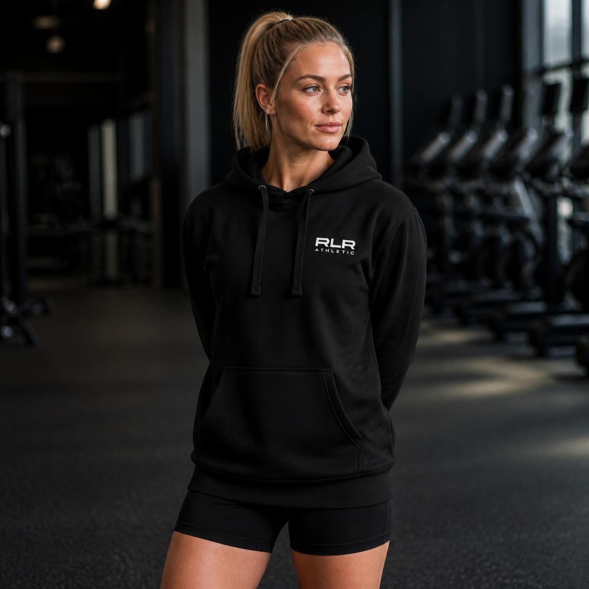 Female athlete wearing the black RLR Athletic Recovery Hoodie in a gym