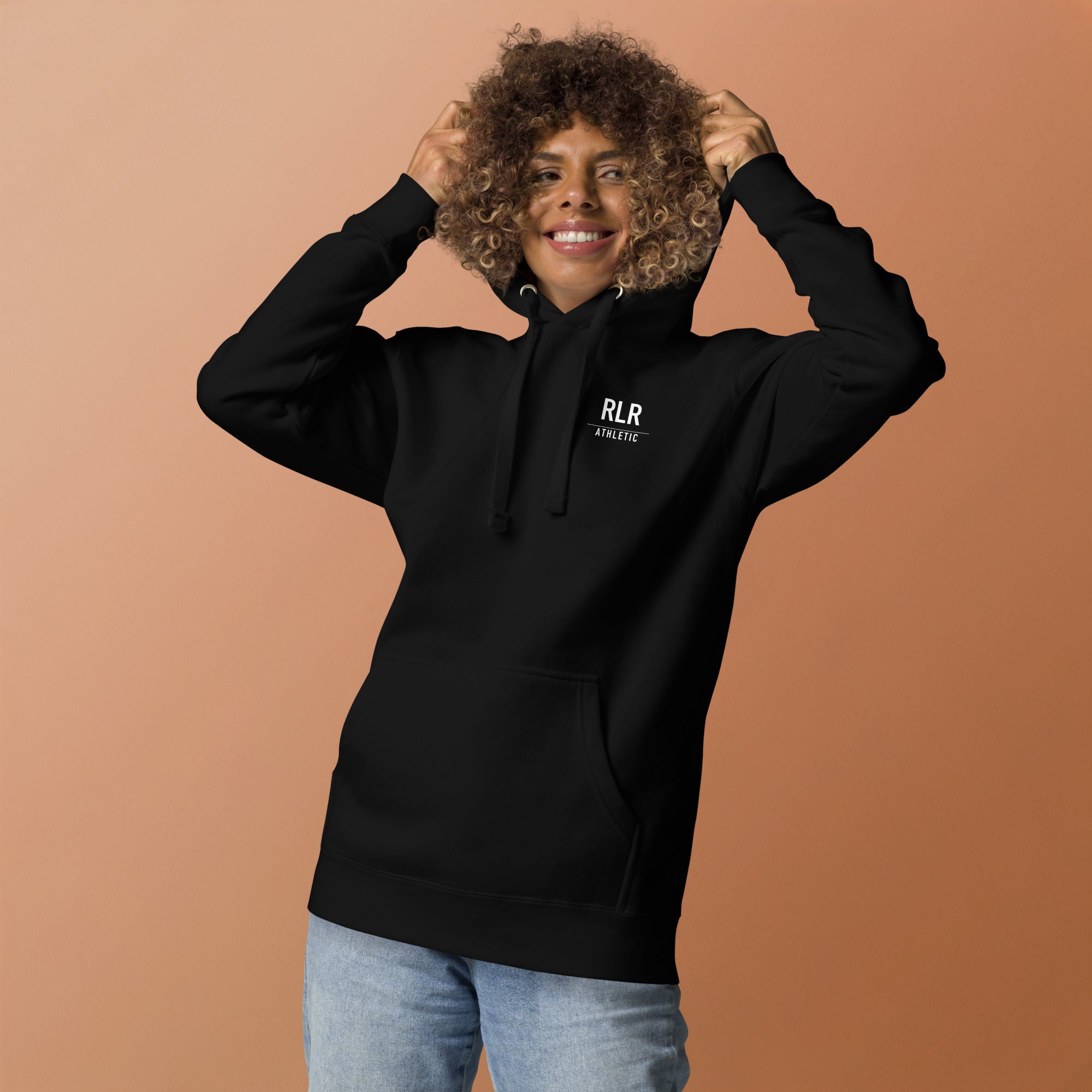 Athlete smiling in the black RLR Recovery Hoodie against a warm studio backdrop
